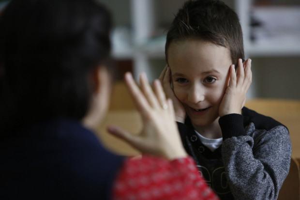 In this photo taken Thursday, Feb. 4, 2016, Bosnian boy Zejd Coralic, right, learns sign language from teacher Anisa Setkic-Sendic in a class at an elementary school in Sarajevo, Bosnia. In 2003, Bosnia adopted laws that allow children with disabilities to be fully integrated into society, including schools. Children with special needs are supposed to have professional assistants who sit with them in class, translating or otherwise helping them participate. But in practice, impoverished Bosnia barely has enough money to keep normal schools functioning and children with disabilities are left to the care and imagination of their parents and the good will of school staff. (AP Photo/Amel Emric)