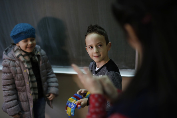 In this photo taken Thursday, Feb. 4, 2016, Bosnian boy Zejd Coralic, center, learns sign language from teacher Anisa Setkic-Sendic, right, in a class at an elementary school in Sarajevo, Bosnia. In 2003, Bosnia adopted laws that allow children with disabilities to be fully integrated into society, including schools. Children with special needs are supposed to have professional assistants who sit with them in class, translating or otherwise helping them participate. But in practice, impoverished Bosnia barely has enough money to keep normal schools functioning and children with disabilities are left to the care and imagination of their parents and the good will of school staff. (AP Photo/Amel Emric)