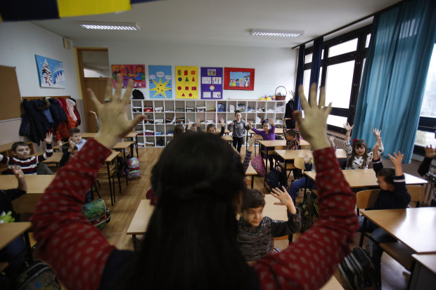 In this photo taken Thursday, Feb. 4, 2016, Bosnian Anisa Setkic-Sendic, a sign language teacher, explains sign language to children at an elementary school in Sarajevo, Bosnia. In 2003, Bosnia adopted laws that allow children with disabilities to be fully integrated into society, including schools. Children with special needs are supposed to have professional assistants who sit with them in class, translating or otherwise helping them participate. But in practice, impoverished Bosnia barely has enough money to keep normal schools functioning and children with disabilities are left to the care and imagination of their parents and the good will of school staff. (AP Photo/Amel Emric)