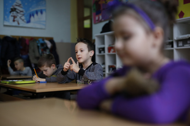 In this photo taken Thursday, Feb. 4, 2016, Bosnian boy Zejd Coralic, center, participates in a class with other children at an elementary school in Sarajevo, Bosnia. In 2003, Bosnia adopted laws that allow children with disabilities to be fully integrated into society, including schools. Children with special needs are supposed to have professional assistants who sit with them in class, translating or otherwise helping them participate. But in practice, impoverished Bosnia barely has enough money to keep normal schools functioning and children with disabilities are left to the care and imagination of their parents and the good will of school staff. (AP Photo/Amel Emric)